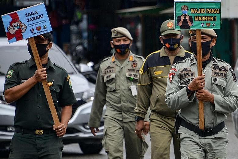 Municipal officers carrying signs to encourage people to wear masks and maintain social distancing amid the coronavirus outbreak in Banda Aceh yesterday. PHOTO: AGENCE FRANCE-PRESSE