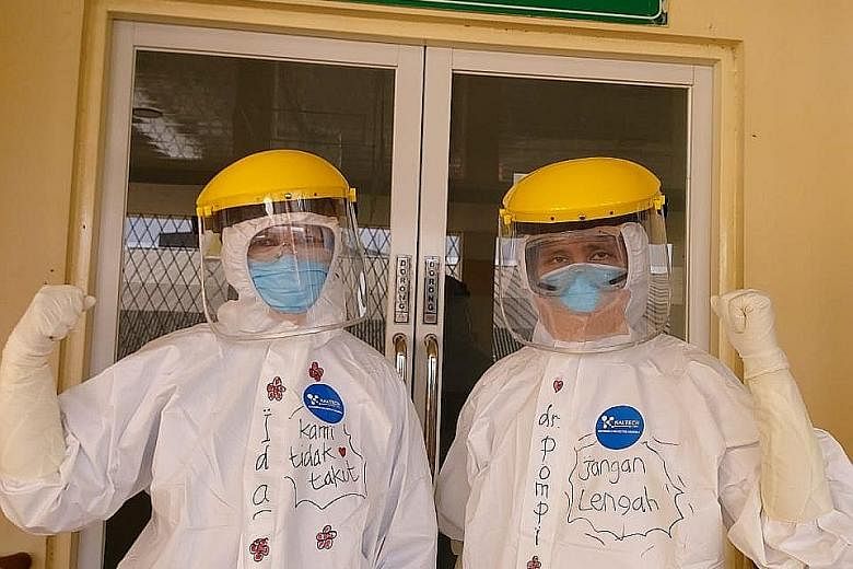 Pulmonologist Pompini Agustina Sitompul (at right) at the Sulianti Saroso Infectious Diseases Hospital in Jakarta. She is wearing a protective suit on which is written "Don't be careless", while her colleague's suit reads "We are not afraid". PHOTO: 