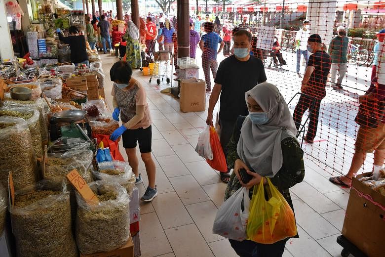 People shopping inside Geylang Serai Market yesterday while snaking queues formed outside to enter. It is one of four wet markets that had imposed entry curbs allowing people to visit only on odd or even dates. Starting yesterday, weekend curbs were 