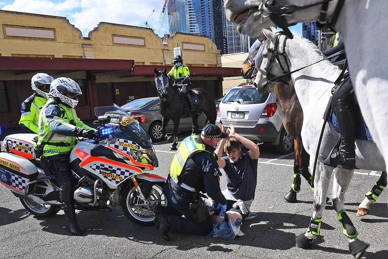 The police detaining an anti-lockdown protester at a rally in Melbourne's Queen Victoria Market yesterday.