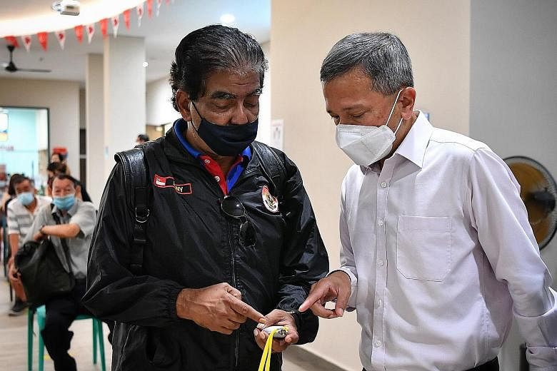 Minister-in-charge of the Smart Nation Initiative Vivian Balakrishnan speaking to security officer Ajid Kumar (far left) after he collected his TraceTogether token at Jalan Besar Community Club yesterday. Mr Kumar made the hour-long journey to the CC