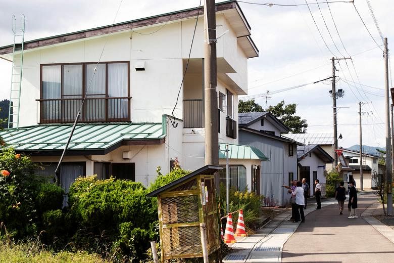 People taking pictures of Mr Yoshihide Suga's childhood home in Yuzawa, Akita prefecture, last Friday. The house has been empty since Mr Suga's ageing mother moved to a nursing home three years ago. Shuttered shops in Yuzawa highlight the challenges 