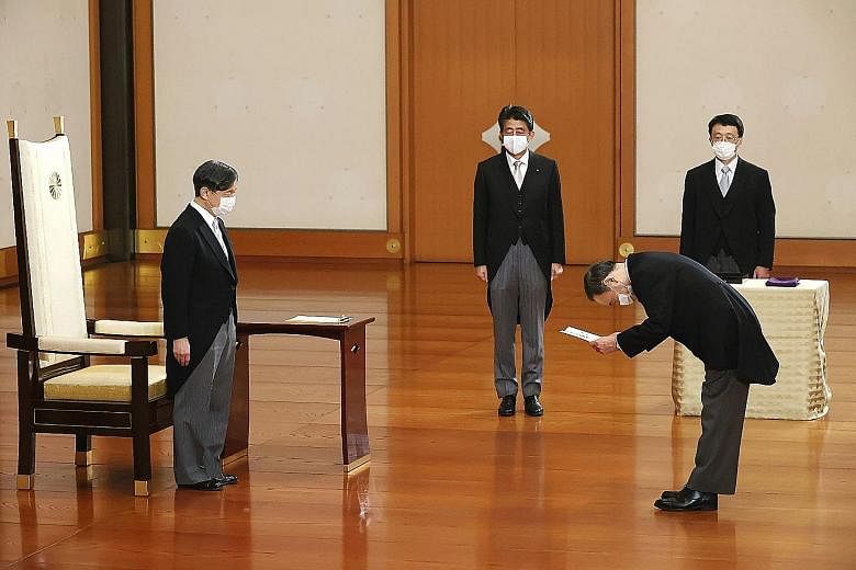 Japan's new Prime Minister Yoshihide Suga receiving a certificate from Emperor Naruhito as outgoing PM Shinzo Abe (third from right) looked on at a ceremony at the Imperial Palace in Tokyo yesterday.