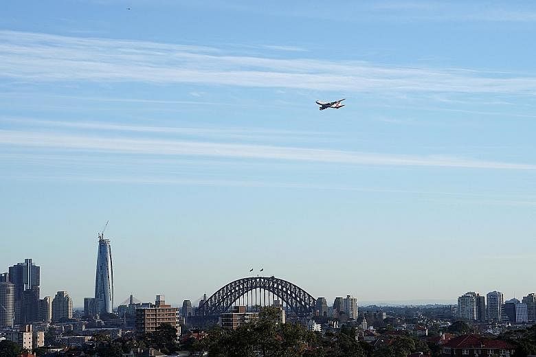 A Qantas plane flying over Sydney. The airline's scenic flights to nowhere will start and end in Sydney, and involve flying at low levels over Uluru, the Great Barrier Reef and Sydney Harbour.