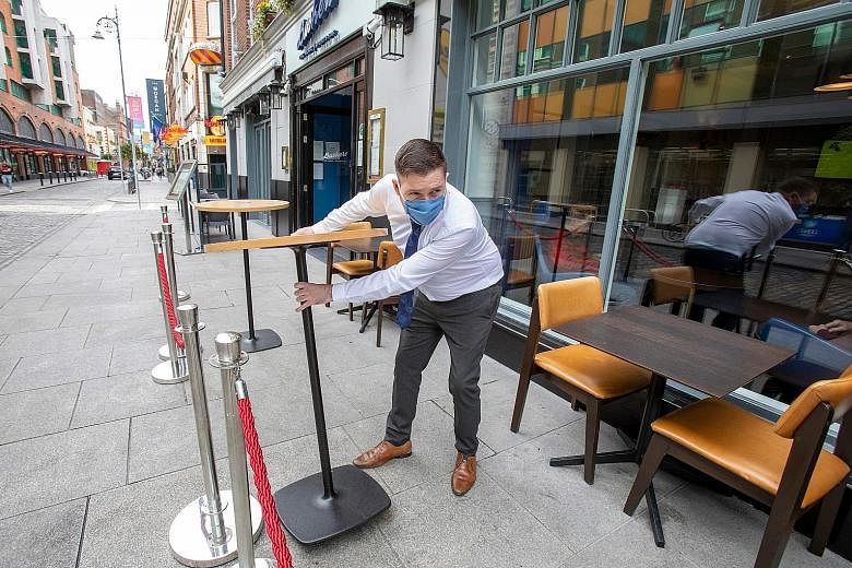 An employee setting out tables outside a pub as restrictions were tightened in Dublin for the second time in a week on Friday.