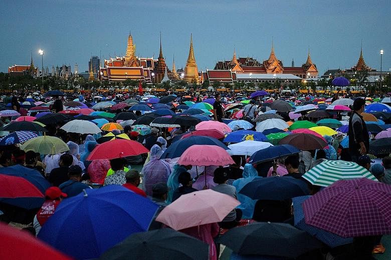 Protesters gathering yesterday in the rain in Sanam Luang, a field next to the Grand Palace, during a pro-democracy rally in Bangkok. PHOTO: AGENCE FRANCE-PRESSE