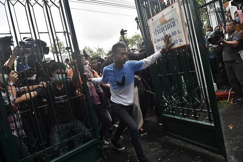Above: Anti-government protesters, led by activist Panupong Jadnok (centre), breaking through a gate at Thammasat University in Bangkok yesterday. Left: Student Union of Thailand spokesman Panusaya Sithijirawattanakul (centre) speaking via a loudspea