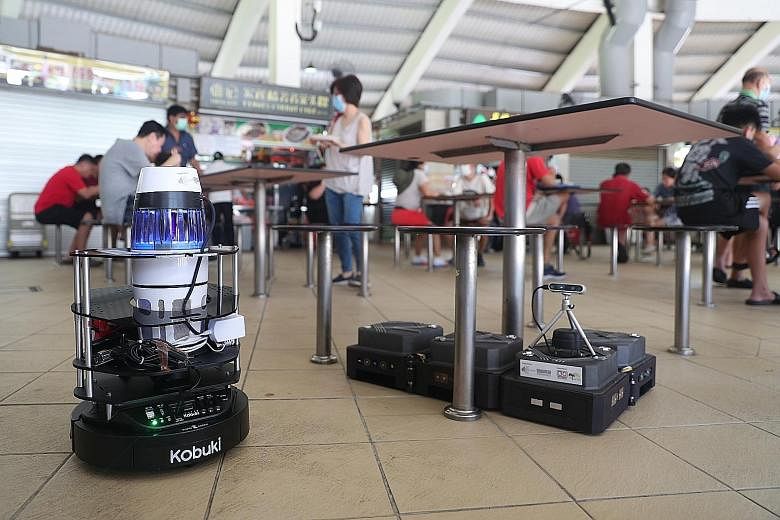 The robots being test-bedded at Tampines Round Market and Food Centre perform tasks like mapping the density of mosquitoes in the surroundings (left) and cleaning the floor.