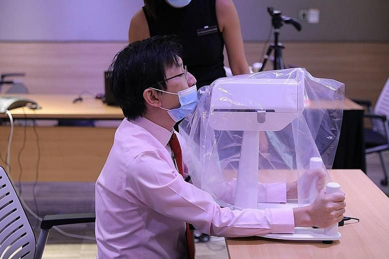 Dr Luke Tay, a consultant at SGH who was part of the team that developed the robot, demonstrating how a patient would position himself when undergoing a swab test done by the SwabBot.