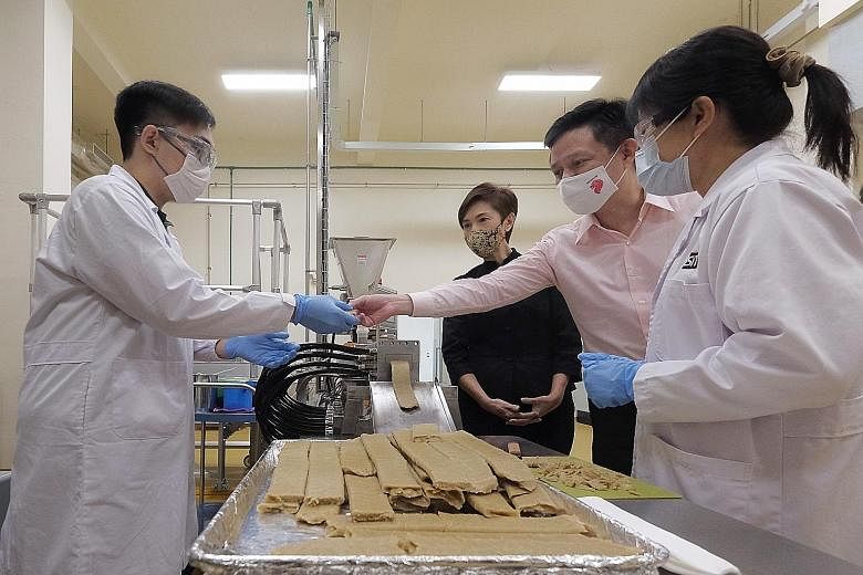 Minister for Trade and Industry Chan Chun Sing and Minister for Manpower Josephine Teo watching as an extruder machine made mock meat during a tour of food manufacturer KH Roberts' facility yesterday. The food manufacturing and service industry is ex