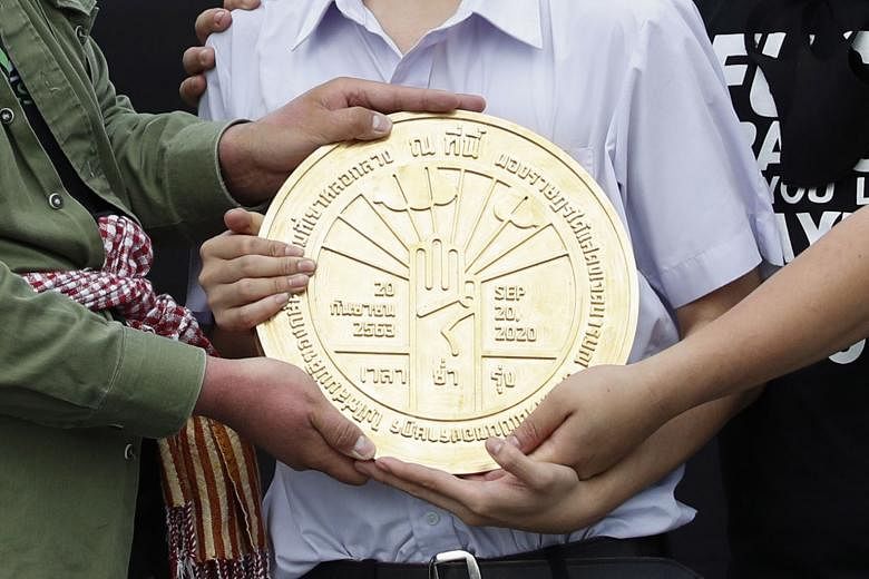 Protesters holding the symbolic plaque before it was installed near Bangkok's Grand Palace on Sunday after a mass rally. Yesterday, they voiced little surprise that it had been removed after less than a day.
