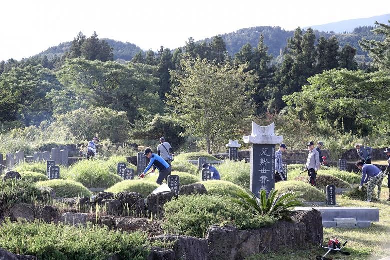 Visitors clearing the grass around their ancestors' graves on Jeju island, South Korea, last Sunday. On Monday, the government announced that all 11 national cemeteries will be closed from Sept 30 to Oct 4.