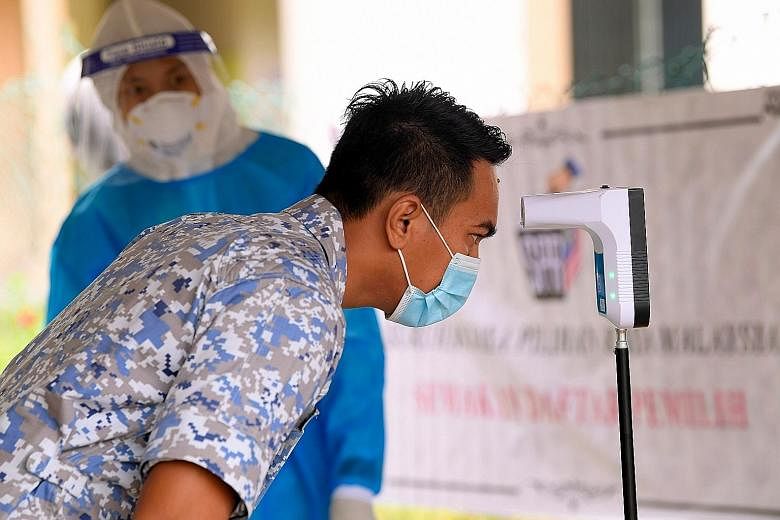 A member of the Malaysian military having his temperature checked before being able to cast his ballot during early voting in the Sabah state election on Tuesday. PHOTO: BERNAMA