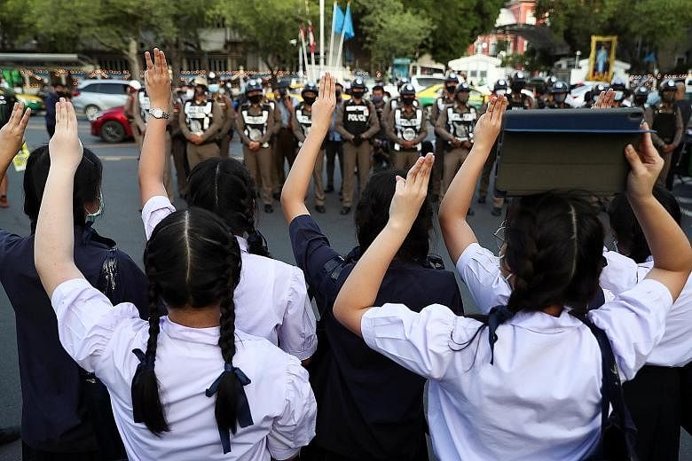 A high schooler making the three-finger salute in support of the student-led democracy movement, outside the Education Ministry in Bangkok last month. PHOTO: REUTERS