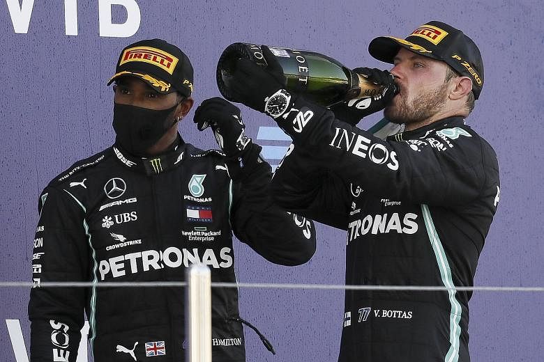 A frustrated Lewis Hamilton on the Sochi podium yesterday, while Mercedes teammate toasted his second Russian Grand Prix title which cut the deficit in the drivers' race to 44 points. PHOTO: EPA-EFE