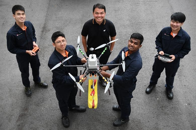 ITE aerospace avionics lecturer Soh Kee Teck (centre) and students (from left) Stephen Ong, Erhan Harith Abdul Malik, Sanjay Shagaran and Kenneth Ng with a drone they are developing to patrol beaches. It carries a float that can be dropped near a swi