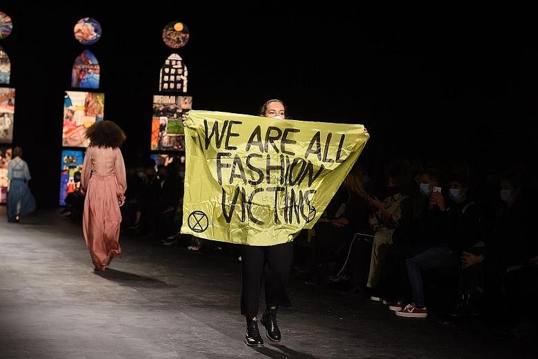 The protester with her sign as she walked the runway at Christian Dior's show in Paris on Tuesday. She left without being challenged, leaving some confused over whether it was a stunt or part of the show. PHOTO: AGENCE FRANCE-PRESSE