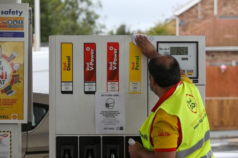 A worker cleaning a pump at a Royal Dutch Shell fuel filling station in Rayleigh in Britain. Job cuts of 7,000 to 9,000 are expected by the end of 2022, including around 1,500 people taking voluntary redundancy this year, Shell said yesterday in a st