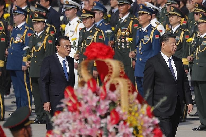 Mr Li gave a speech on Wednesday at the Great Hall of the People. Mr Xi (seated, left) also attended the event. Chinese President Xi Jinping (right) and Premier Li Keqiang arriving on Wednesday for the flower-basket-laying ceremony at the monument to