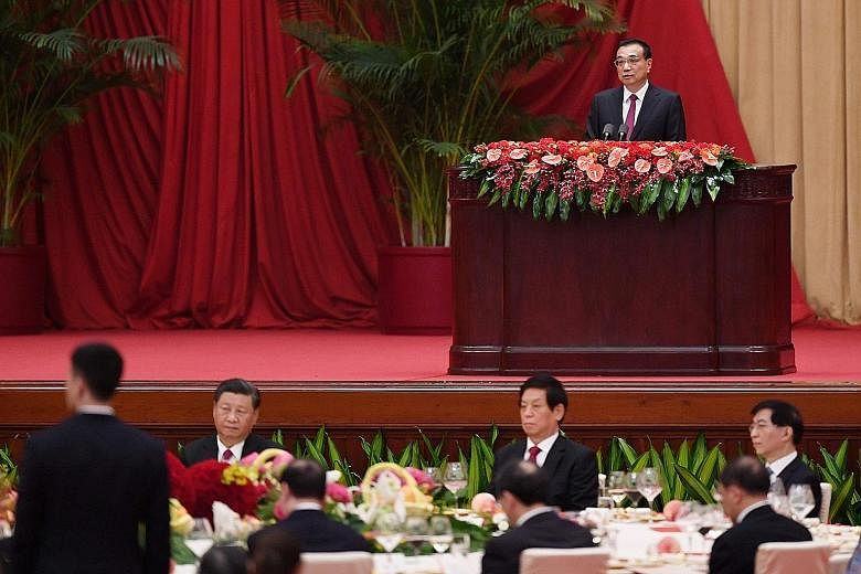 Mr Li gave a speech on Wednesday at the Great Hall of the People. Mr Xi (seated, left) also attended the event. Chinese President Xi Jinping (right) and Premier Li Keqiang arriving on Wednesday for the flower-basket-laying ceremony at the monument to