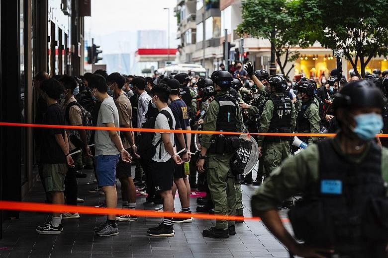 Riot police detaining people in Hong Kong yesterday as they patrolled the route of a banned anti-government march. More than 50 people had their wrists bound with plexicuffs before being put on buses. Protesters wanted to march against Beijing's impo