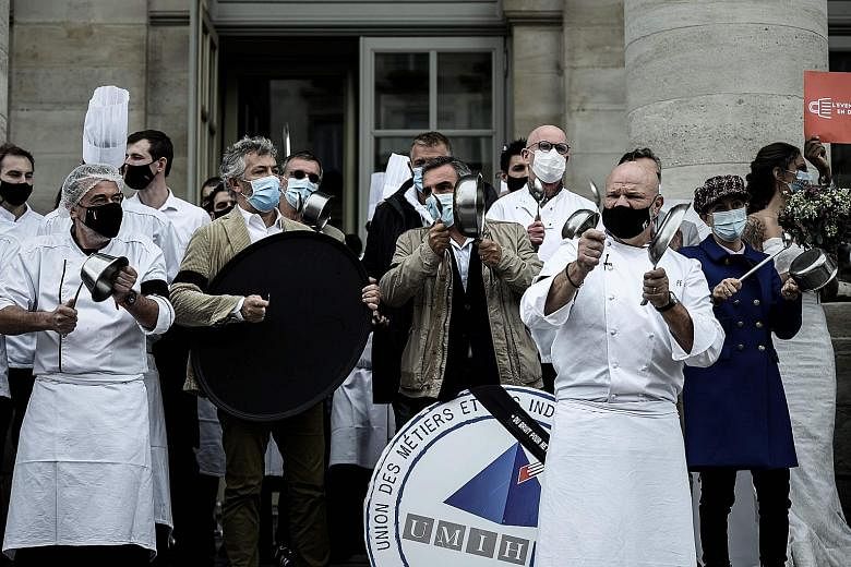 Chef Philippe Etchebest (above, foreground) of Bordeaux restaurant Le Quatrieme Mur and his employees protesting yesterday against the French government's plans to close bars and restaurants in Paris and its nearby suburbs. Meanwhile, in Italy, the a