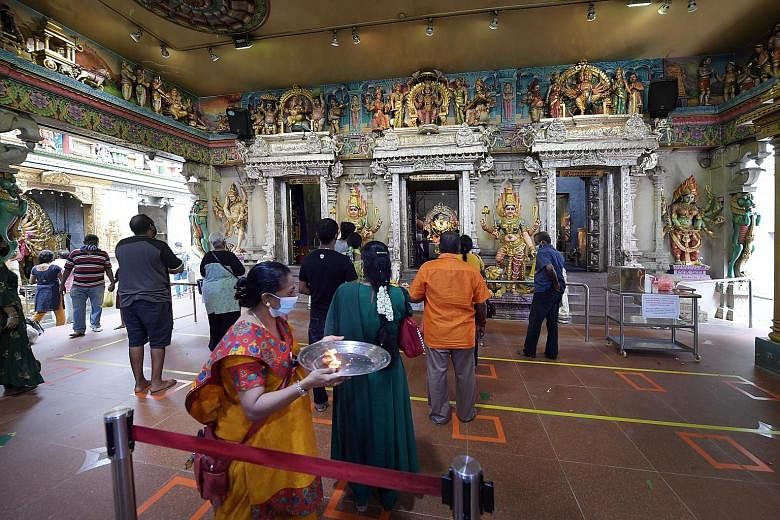 Left: Devotees praying outside Kwan Im Thong Hood Cho Temple, which remained closed yesterday. Far left: Worshippers at Sri Vee-ramakaliamman Temple in Little India yesterday finally got to attend prayers where live music was played.