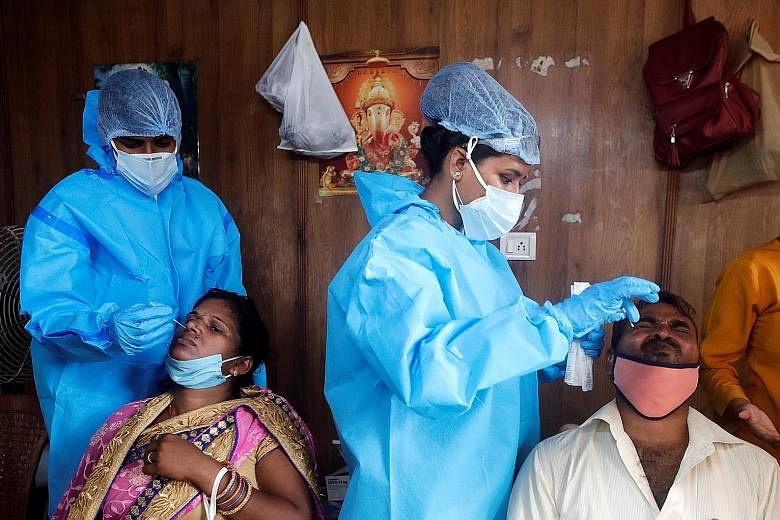 Healthcare workers collecting swab samples from migrants who returned from their hometowns, at a railway station on the outskirts of Mumbai on Saturday. As the Covid-19 pandemic rages on in India, medical workers have been feeling the strain with som