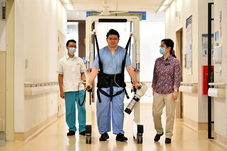 Dr Tay San San (right) and therapy assistant Muhammad Iylia Razalee (left), with a staff member demonstrating the use of the robotic walking aid, called Andago, which is primarily used for stroke patients. ST PHOTO: LIM YAOHUI
