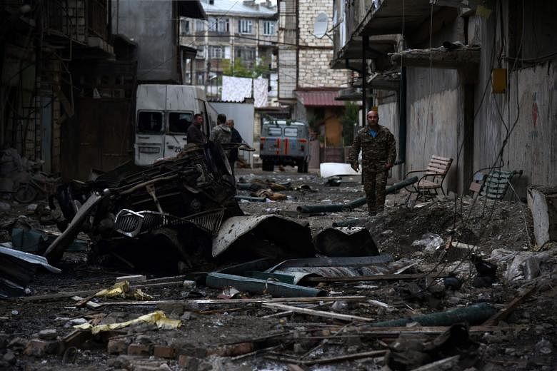 Above: The aftermath of recent shelling during the ongoing fighting between Armenia and Azerbaijan over the breakaway Nagorno-Karabakh region, in the disputed region's main city of Stepanakert on Sunday. Left: People seeking shelter in the basement o
