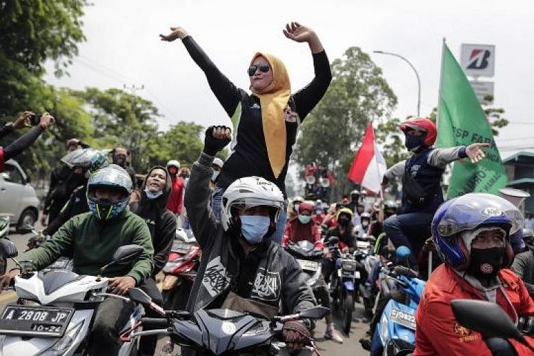 Thousands of workers in Indonesia, including in Tangerang (above), took to the streets yesterday morning, carrying flags and banners that read "Bring down the job creation law".