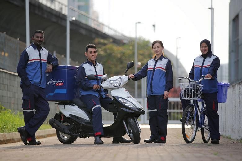 From left: SingPost staff Mageswaran Arumugam, 37; Muhammad Aizuddin Musa, 26; Huo Xiang Xiu, 28; and Paridah Ismail, 51, wearing the new uniform for postmen at the SingPost Centre Regional Base on Wednesday. The new uniform features its corporate colours