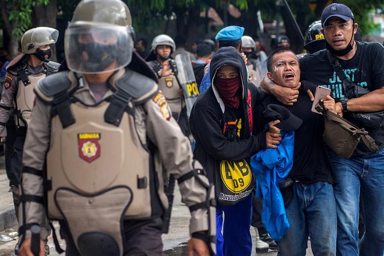 Plain-clothes policemen detaining a student protester at a rally against Indonesia's controversial job creation law in Palu, Central Sulawesi province, on Thursday. Over 3,800 people have been held nationwide during rallies this week that at times tu