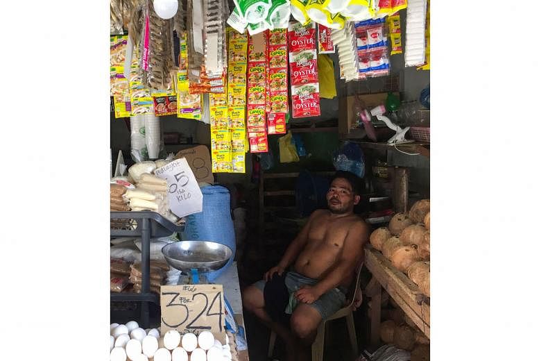 Mr Richard Pontillas resting in his family-owned "sari-sari" or provision shop in Quezon City, the Philippines, in August. The liquid goods he sells used to be packaged in glass, but now he stocks them in plastic sachets. Employees sorting plastic bo