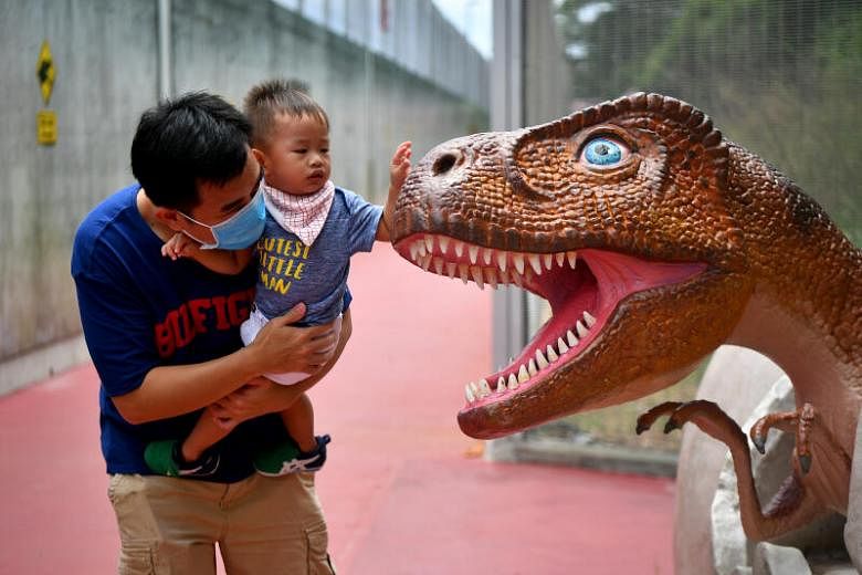 A father letting his child play with a dinosaur at the Changi Jurassic Mile, on Oct 11, 2020.
