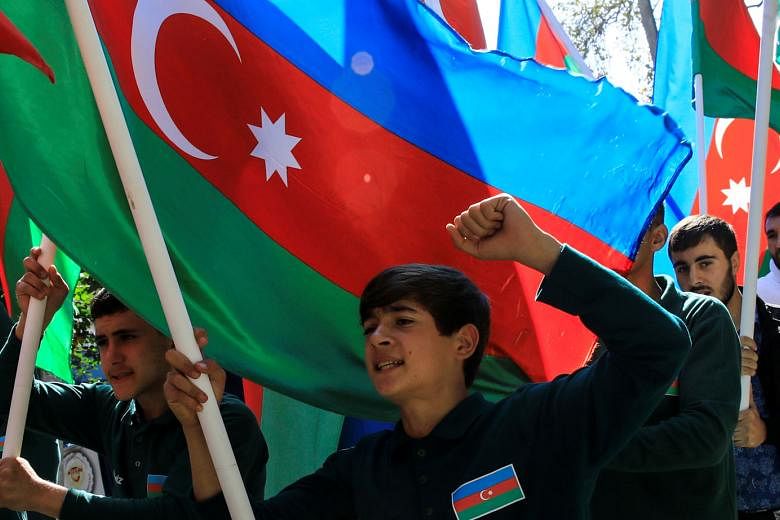 Azeris with their national flags during the funeral on Monday of a couple killed in the fighting over the breakaway region of Nagorno-Karabakh. Hundreds have died in the violence between Armenia and Azerbaijan in the past fortnight. Nagorno-Karabakh is in
