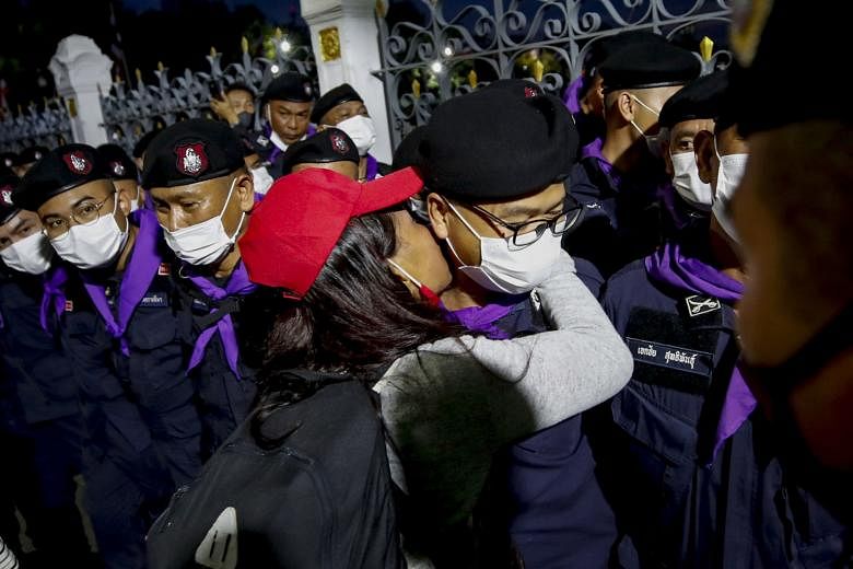 A protester kissing a Royal Thai Police officer guarding Government House in Bangkok during yesterday's mass protest. Pro-democracy demonstrators lighting up their mobile phones as they gathered outside Government House in Bangkok yesterday. They wan