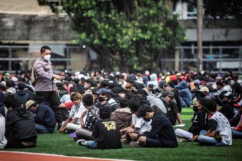 A police officer checking detained demonstrators in Jakarta before releasing them after a protest against the Indonesian government's labour reform Bill yesterday.