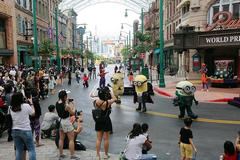 People at Universal Studios Singapore last month. It is mandatory for everyone to wear a mask when they are outside their homes in Singapore. Visitors at Victoria Peak (far left) in July and an employee disinfecting a carousel at Ocean Park (left) la