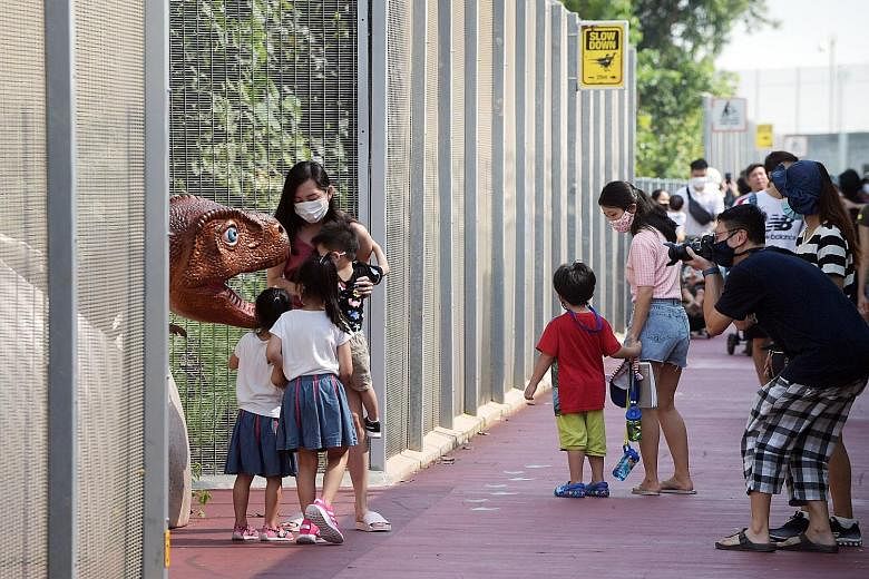 Visitors at the Changi Jurassic Mile between Terminal 4 and the entrance to East Coast Park yesterday morning. The outdoor display of more than 20 dinosaur models has been drawing crowds since it opened last week. Visitors must now reserve a slot on 
