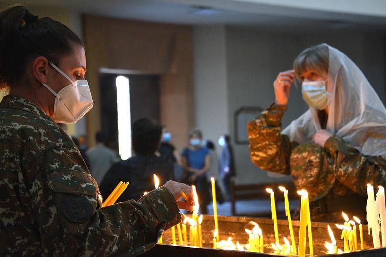 Armenians lighting candles in a church in Yerevan last Saturday for their countrymen killed during fighting over the breakaway region of Nagorno-Karabakh. The truce agreed to last Saturday came into force at midnight after a week-old Russian-brokered