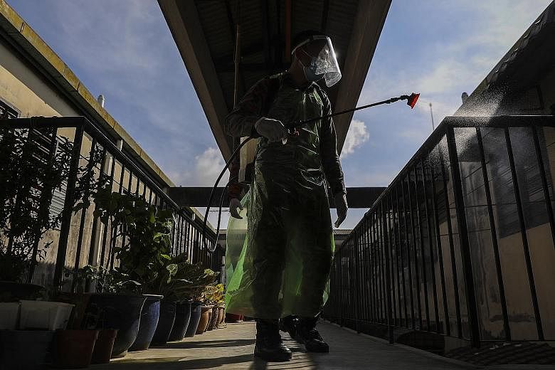 A Malaysian Fire and Rescue Department officer sanitising an area outside a block of apartments in Shah Alam, Selangor, yesterday. The country recorded 865 cases yesterday, the third consecutive day when daily infections were above 800. The governmen