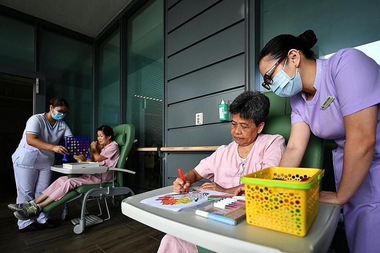 Staff nurse Cabreros Maria Fatima Nicolas (far left) and senior patient care assistant Bote Robenny Bovida (right) at a demonstration of a therapy session yesterday at Changi General Hospital's dementia ward. A survey at the ward found that more pati