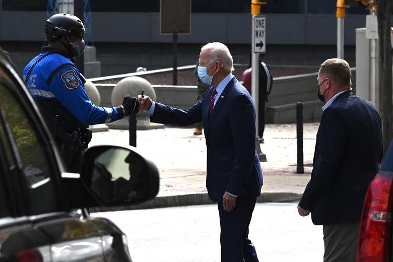 Democratic presidential candidate Joe Biden with a police officer in Delaware on Monday. The change to the final debate comes after US President Donald Trump repeatedly talked over Mr Biden and the moderator at last month's debate.