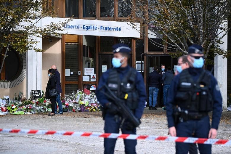 Flowers placed outside the Bois d'Aulne secondary school on Monday in homage to slain history teacher Samuel Paty, who was beheaded by an attacker last Friday in Conflans-Sainte-Honorine, north-west of Paris, for showing students cartoons of Prophet 
