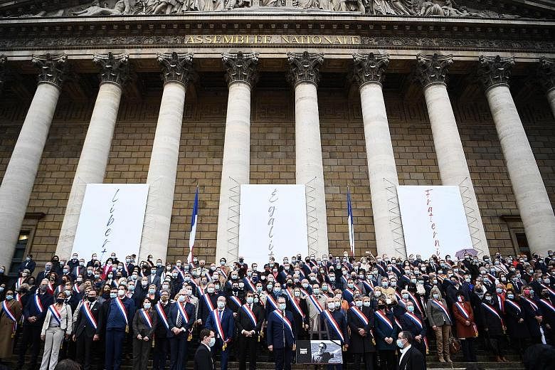 French MPs paying tribute, in front of the Palais Bourbon in Paris on Tuesday, to history teacher Samuel Paty, who was beheaded by an attacker for showing students cartoons of Prophet Muhammad in class.