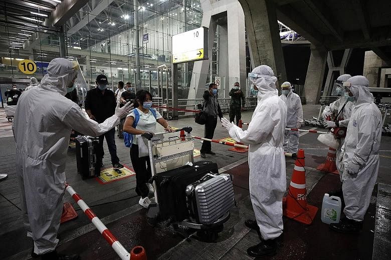 Chinese tourists going through arrival measures at Suvarnabhumi Airport on Tuesday. Thirty-nine tourists from Shanghai arrived on Tuesday night. Thai health officials in full protective equipment disinfecting the luggage of Chinese tourists upon thei