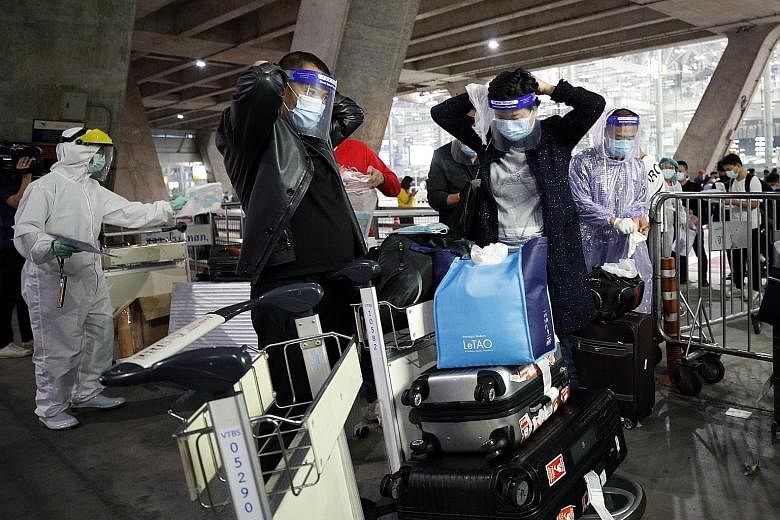 Chinese tourists in raincoats and face shields boarding a bus at Suvarnabhumi Airport heading to their hotels for the mandatory 14-day quarantine on Tuesday. New tourist arrivals in Thailand must quarantine for two weeks and test negative three times