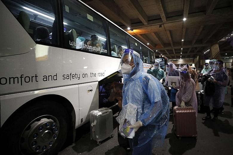 Chinese tourists putting on raincoats and face shields as part of Thailand's coronavirus pandemic restrictions at Suvarnabhumi Airport on Tuesday.