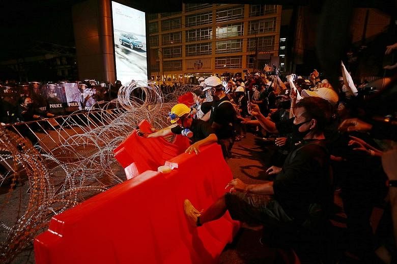 Anti-government protesters trying to break through police barricades in Bangkok yesterday. The rallies - led largely by youth who are calling for the Constitution to be amended, Thai Prime Minister Prayut Chan-o-cha to resign and the monarchy to be r